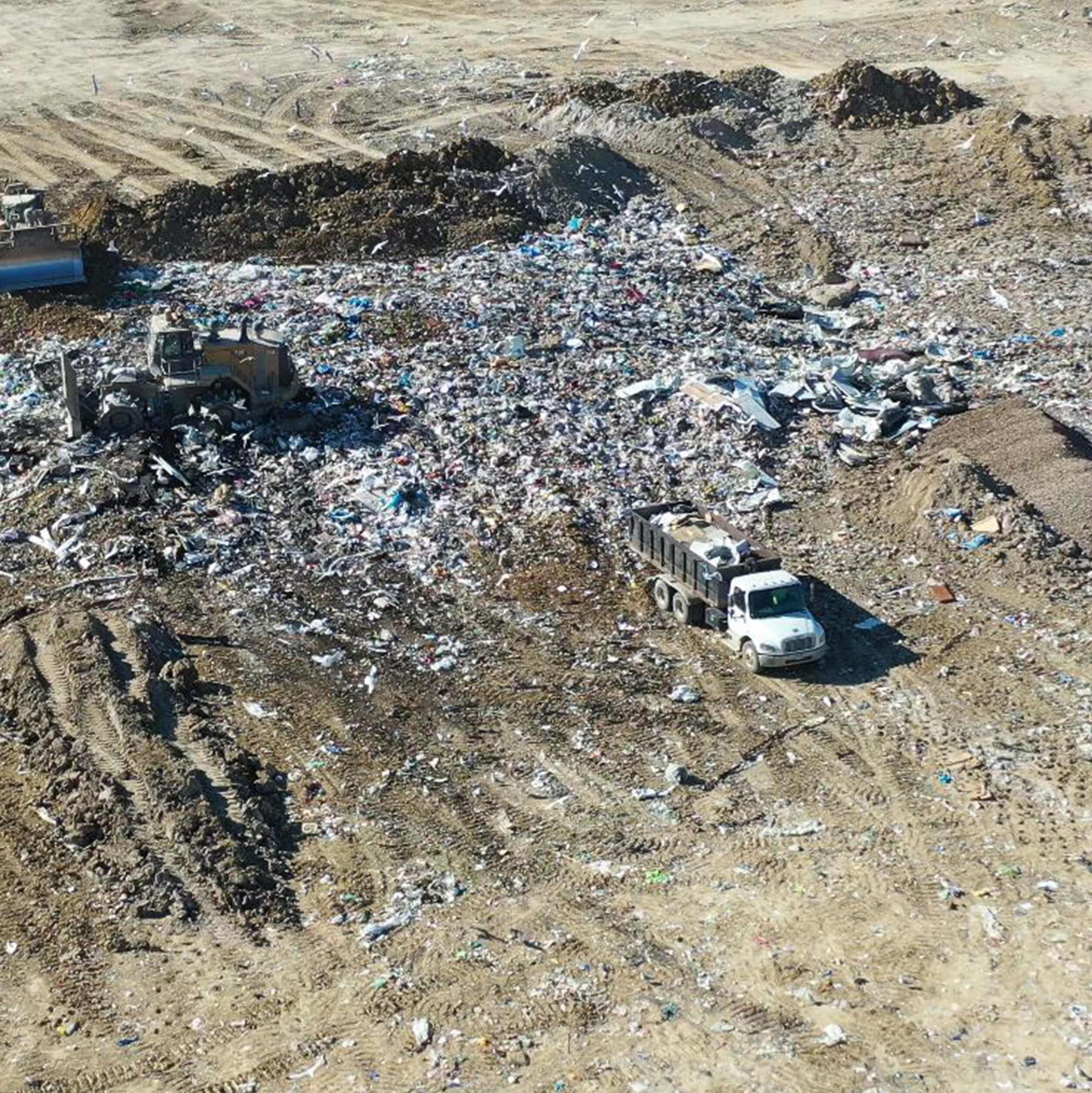 Bulldozer and truck moving waste in a landfill