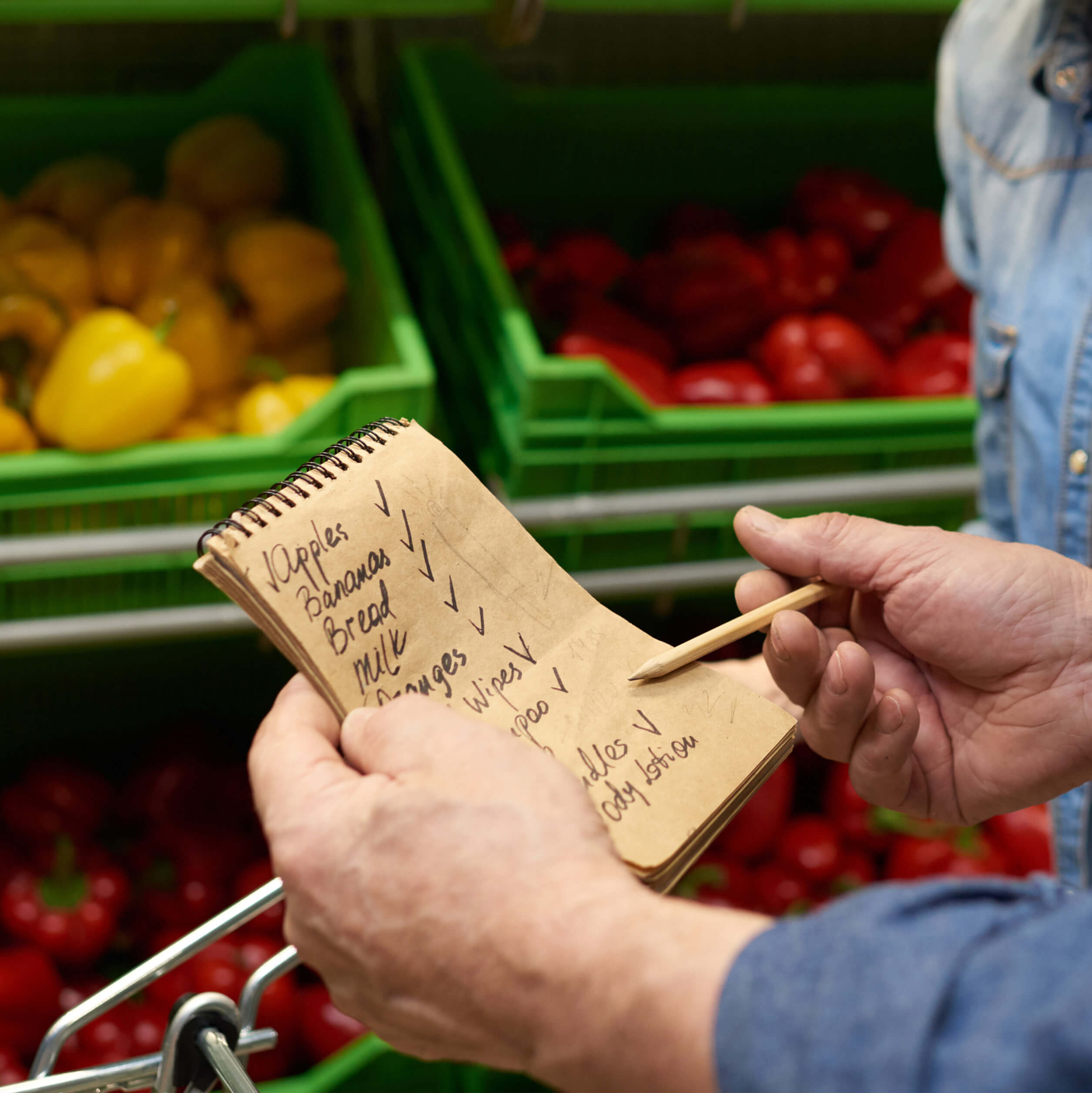 Person holding grocery shopping list in produce section of a store